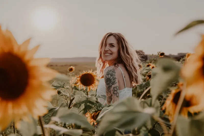 Fotografin lächelt über die Schulter in einem Sonnenblumenfeld