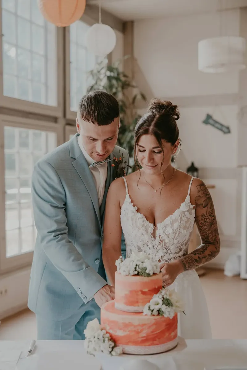 Brautpaar schneidet gemeinsam die zweistöckige Hochzeitstorte an